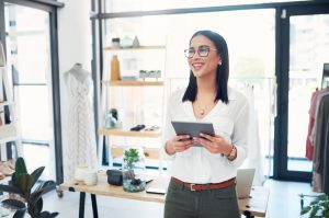 Cropped shot of a young business owner using her tablet while standing in her store