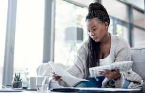 Shot of a young woman going over paperwork on the sofa at home